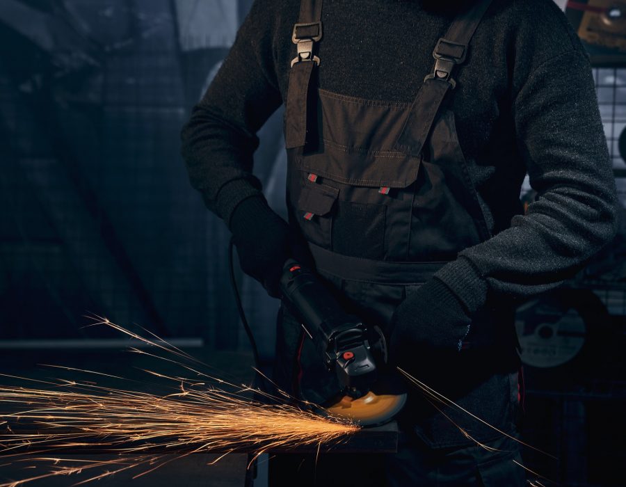 Man in black suit polishing metal with angle grinder
