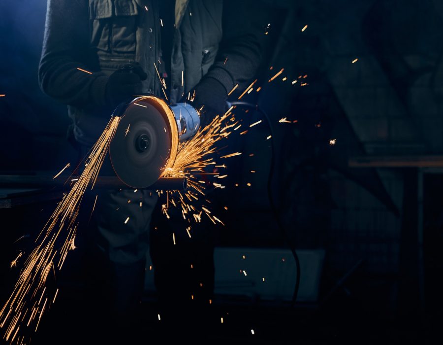Young man cutting with rotating disc for metal with sparks